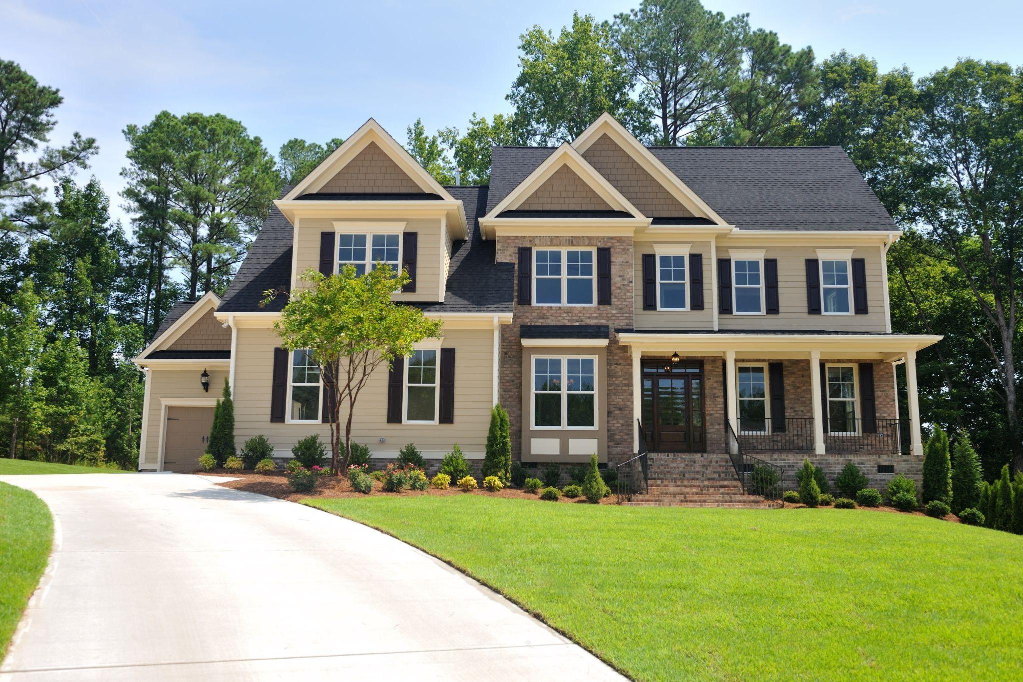 brown house with lawn and curved driveway
